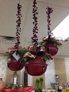 three hanging christmas balls with bows and berries on them in a kitchen area, decorated for the holiday season