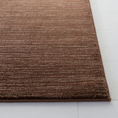 a brown area rug on the floor with white tiles in the backgroung