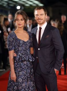 a man and woman standing next to each other on a red carpet at an event