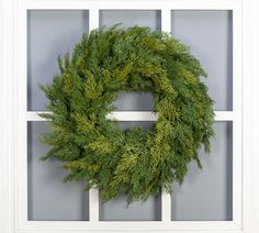 a green wreath is hanging on the window sill in front of a gray wall