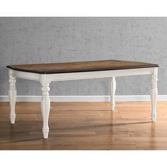 a wooden table with white legs and a black top on a hard wood floor in front of a gray wall