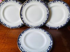 four blue and white plates sitting on top of a wooden table