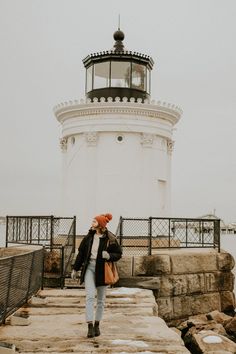 a woman is standing on the steps to a light house with a red scarf around her head