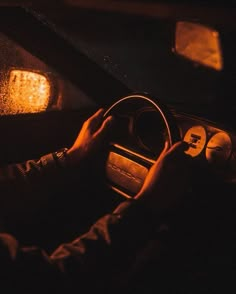 a person driving a car at night in the dark with their hands on the steering wheel