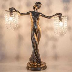 a bronze statue holding two crystal chandeliers in it's arms and hands