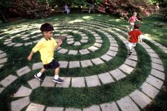 a young boy is running in the middle of a circular stone path that has grass on it