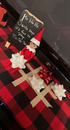 an elf is sitting on top of a table with paper flowers and a sign that says ho ho ho