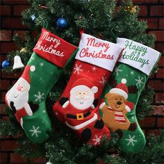 three christmas stockings hanging from a tree with santa and other holiday decorations on it's sides