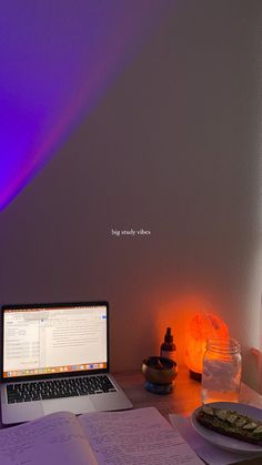 an open laptop computer sitting on top of a desk next to a plate of food