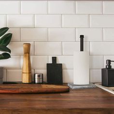 a wooden cutting board sitting on top of a counter next to a potted plant