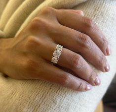 a woman's hand with a diamond ring on her left wrist, wearing a white sweater