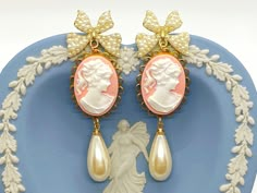 "These beautiful vintage inspired earrings were created with the sweetest pearl bow post earrings adorned with brass scalloped settings with pink and white Cameo cabochons and vintage cream teardrop pearls. These cameo statement earrings hang beautifully from the ear and measure 2 3/4 inches in length and 7/8 inches in width. These earrings make the \"perfect gift\" for your mom, sister, daughter, friend, girlfriend, wife or bridesmaids....She will truly love these and treasure them for many yea Pink Dangle Pearl Earrings For Formal Occasions, Pink Pearl Earrings For Pierced Ears, Elegant Handmade Pink Clip-on Earrings, Pink Feminine Pearl Earrings, Elegant Cameo Dangle Earrings, Pink Pearl Bridal Earrings As Gift, Pink Pearl Bridal Earrings For Gift, Victorian Pearl Earrings For Pierced Ears, Pink Victorian Earrings For Gift