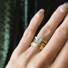 a close up of a person's hand with two wedding rings on their fingers