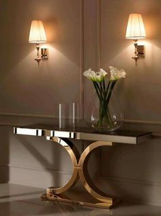 a vase with flowers sitting on top of a table next to two wall sconces