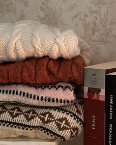 a stack of sweaters sitting on top of a table next to a book