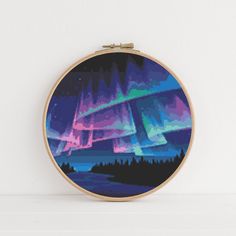 a cross stitch pattern with an aurora bore in the sky on a wooden hoop frame