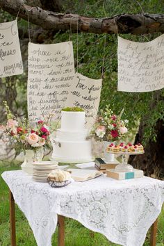 a table topped with a white cake covered in frosting next to a forest filled with trees