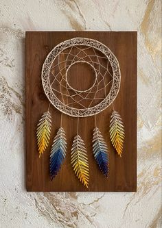 a wooden wall hanging with a colorful dream catcher on it's side and an intricate wire frame