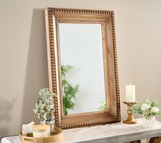 a mirror sitting on top of a table next to a candle