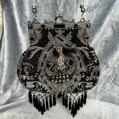 a black and white purse with chains hanging from it's sides on a gray background