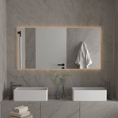 a bathroom with two sinks, a mirror and towels on the counter in front of it