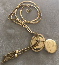 "Vintage A-C 12K Gold-filled Locket Tassel Lariat Pendant Necklace. Size: Necklace- 29\"x 3/16\"(3mm). Locket: 1\"x1 1/4\" round. Markings: A-C 1/20 12KT GF. Beautiful. Sold as is. Pre-Owned." Vintage Lariat Necklace With Adjustable Chain For Gifts, Vintage Adjustable Lariat Necklace As Gift, Vintage Yellow Gold Jewelry With Detachable Pendant, Vintage Necklace With Latkans For Gift, Elegant Latkans Necklace As A Gift, Vintage Lariat Chain Jewelry, Gold Lariat Necklace With Detachable Pendant, Elegant Yellow Gold Lariat Necklace In Brass, Elegant Yellow Gold Brass Lariat Necklace