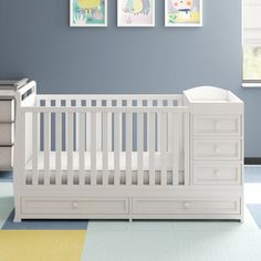 a baby's room with blue walls and white crib in the center, two pictures on the wall