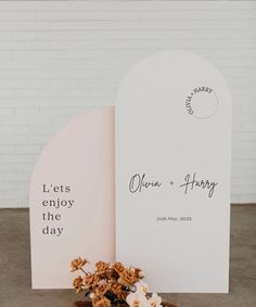 an open book with flowers on it next to a sign that says let's enjoy the day