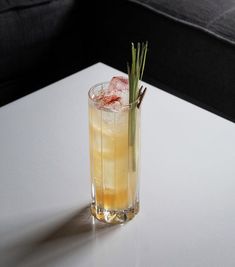 a tall glass filled with lemonade and garnish sitting on a white table