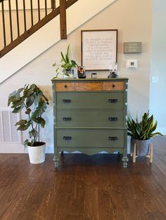 a green dresser sitting in the middle of a living room next to a stair case