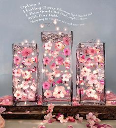 three glass vases with pink flowers in them on a table next to some petals