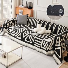 a black and white couch sitting in a living room next to a table with two pillows on it