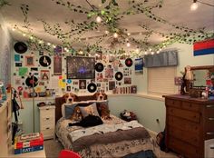 a bedroom with many pictures on the wall and lights hanging from the ceiling above the bed