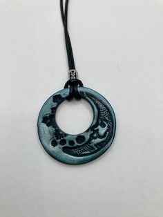 a black and blue necklace with a circular pendant hanging from it's end on a cord