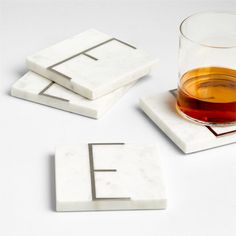 marble coasters with the letter e on them and a glass of tea in front