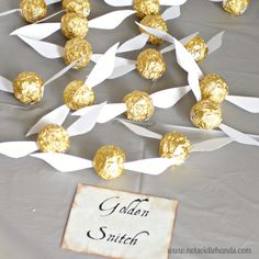 some white and gold foiled candies are on a table next to a sign