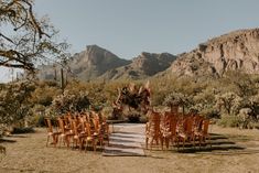 rows of wooden chairs set up in the desert for an outdoor ceremony with mountains in the background