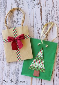 two bags with christmas trees on them are sitting on a wooden surface and tied to twine