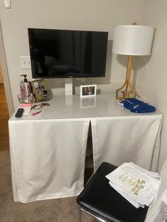 a flat screen tv sitting on top of a white table next to a black chair