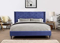 a bed with blue headboard and foot board in a white room next to a rug