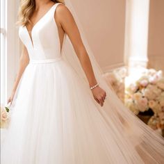 a woman in a wedding dress standing by a window