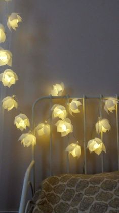 a crib with some lights hanging from it's sides and flowers on the bed