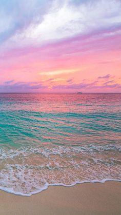 an ocean beach with waves coming in to shore and the sun setting over the water