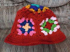 a red crocheted purse sitting on top of a couch next to a pillow