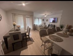 a living room filled with furniture and a flat screen tv mounted to the wall next to a dining table