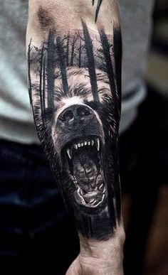 a man's arm with a bear tattoo on it and trees in the background