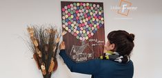 a woman is drawing on the wall next to a vase with flowers and branches in it