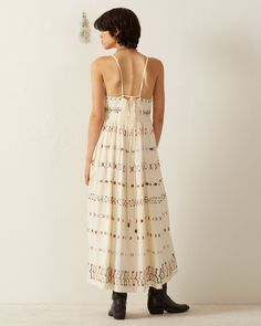 Crafted in Tencel, our ivory sleeveless dress is intricately hand-embroidered throughout with colorful stitching. The lightweight summer dress has a long gathered skirt and a beautiful drape. Lined in cotton, the dress has a cloth-covered button front, adjustable straps, and a smocked back for a comfortable fit. A classic silhouette perfect for warm weather. This one-of-a-kind textile was embroidered by hand. Subtle variations are part of the unique beauty of the garment and a signature of the a Sleeveless Summer Maxi Dress For Gatherings, Sleeveless Maxi Dress For Summer Gatherings, Spring White Maxi Dress For Gatherings, White Spring Maxi Dress For Gatherings, White Maxi Dress For Spring Gatherings, Sleeveless Sundress For Gatherings, Summer Cream Maxi Dress With Smocked Back, Cream Maxi Dress With Smocked Back For Summer, Summer Embroidered Beige Midi Dress