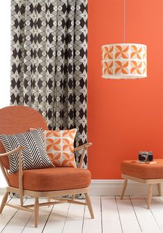 an orange chair and ottoman in front of a window with black and white patterned curtains