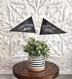 two black and white pennants on top of a wooden table next to a potted plant